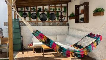 Eine Hängematte unter einer Holzpergola, ein Swimmingpool und eine geflieste Terrassenfläche.