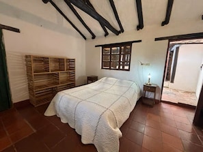 Ein Schlafzimmer mit einem Bett, einem Holzschrank, einem Fenster und einem Nachttisch mit Lampe.