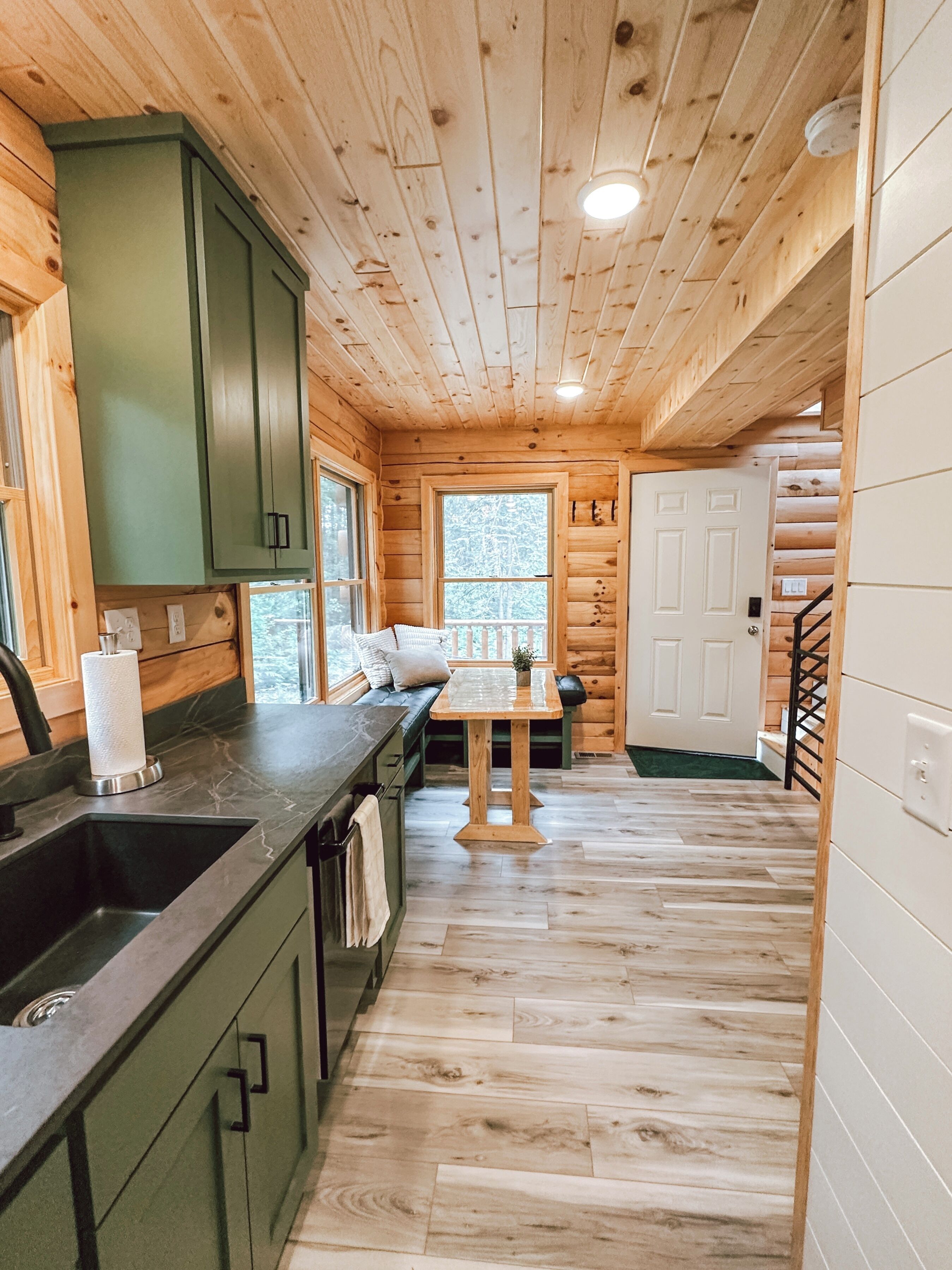 L’intérieur d’une cabane en bois comprend un coin cuisine, une table à manger et un escalier.