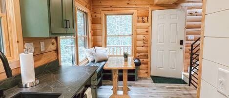 L’intérieur d’une cabane en bois comprend un coin cuisine, une table à manger et un escalier.