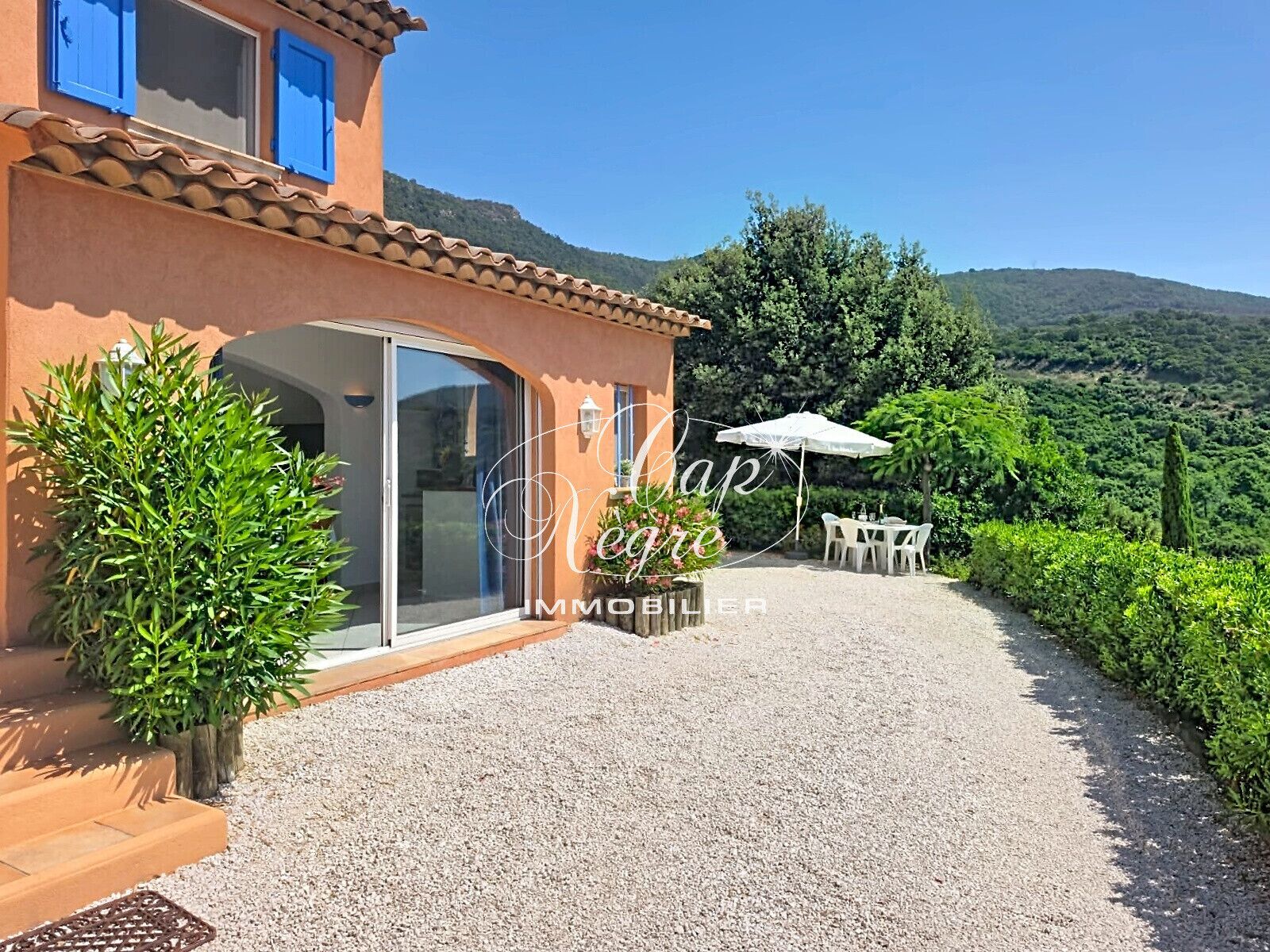A villa with a patio, a dining area, and a view of the surrounding landscape.