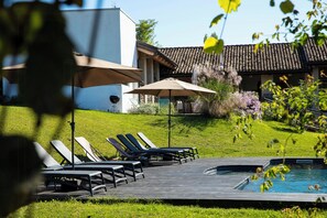 A poolside area with lounge chairs and umbrellas, a small pool, and a building with a tiled roof. - Pool house 5 mins from town among vineyards (Novello)