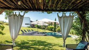 Ein überdachter Außenbereich mit Pool, Liegestühlen und Sonnenschirmen.