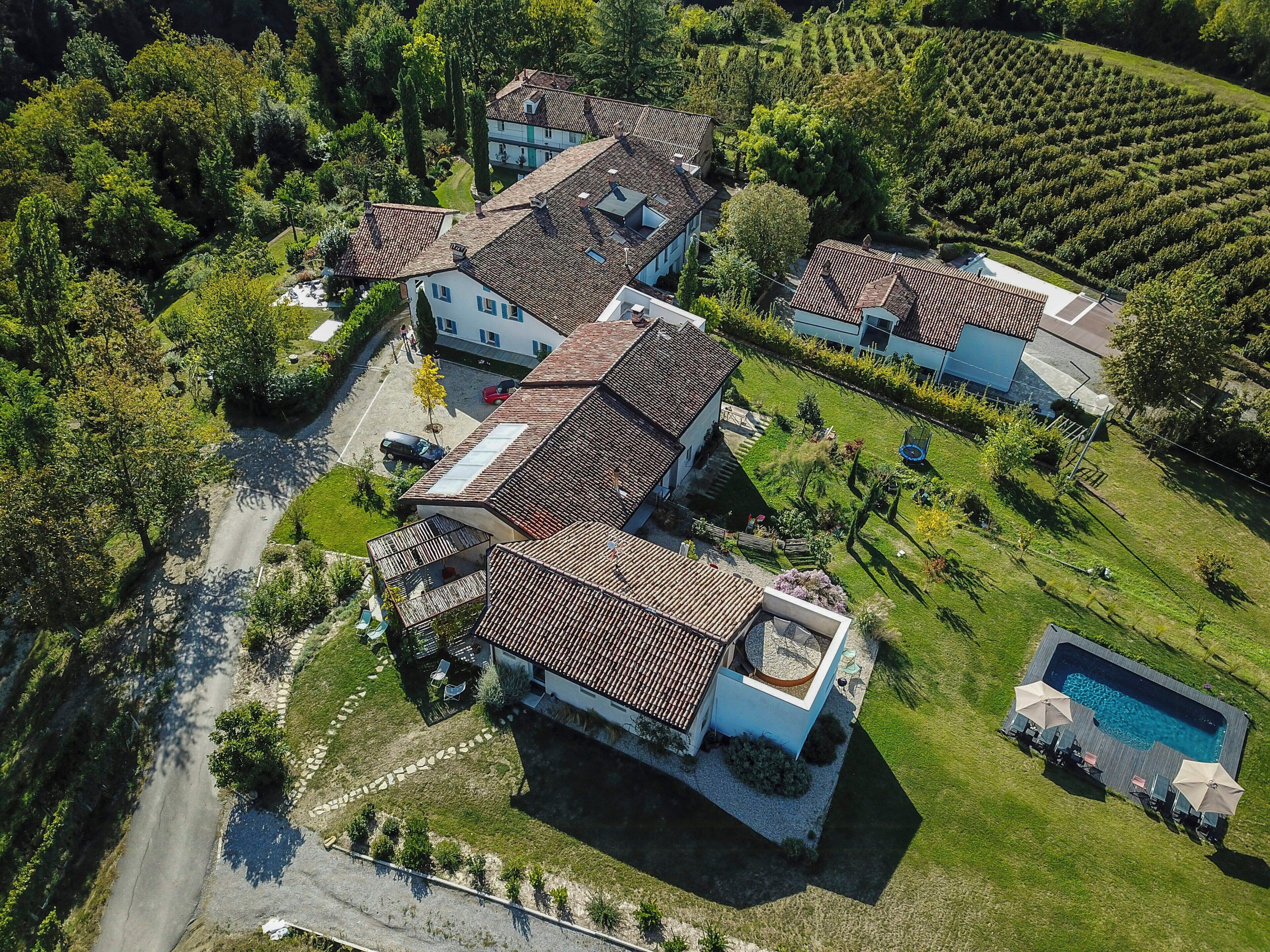 Vista aérea de um bairro residencial com várias casas, uma piscina e um vinhedo.