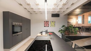 Eine moderne Küche mit Einbauofen, einer zentralen Kochinsel und einem Essbereich mit Stühlen und einem Tisch.