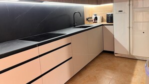 Een moderne keuken met een zwart aanrecht, een spoelbak, een koffieapparaat en een witte koelkast.