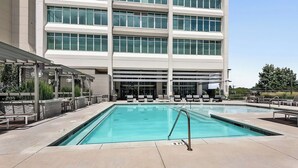 A swimming pool with lounge chairs and a building with large windows in the background. - Relax, Recharge, Explore. Where Luxury Meets Comfort l The Perfect Atlanta Stay (Atlanta)