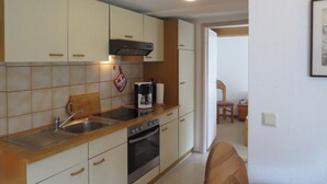 Una cocina con armarios blancos, encimera de madera, cafetera y estufa.