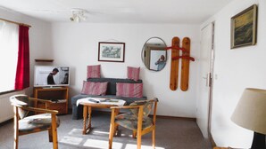 Una sala de estar con sofá, sillones, televisor, espejo y un soporte para esquíes.