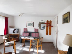 A living room with a sofa, chairs, a television, a mirror, and a ski rack. - Living under a thatched roof, in the quiet neighborhood of Fahretoft, 8 km from the North Sea (Dagebüll)