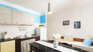 Une cuisine moderne avec un coin repas, un canapé et deux tableaux encadrés au mur.