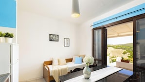 Une chambre à coucher avec un lit, une table sur laquelle est posé un vase, et une vue sur l’extérieur.