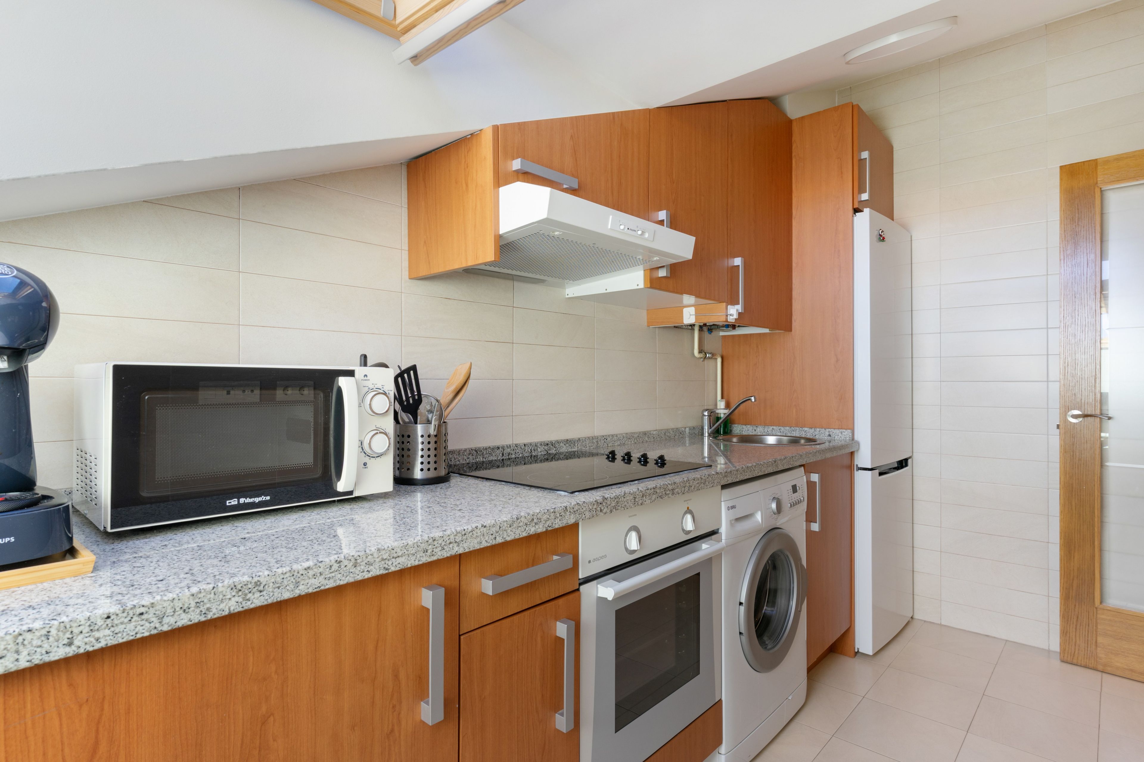 Cocina compacta con microondas, estufa, horno y lavadora.