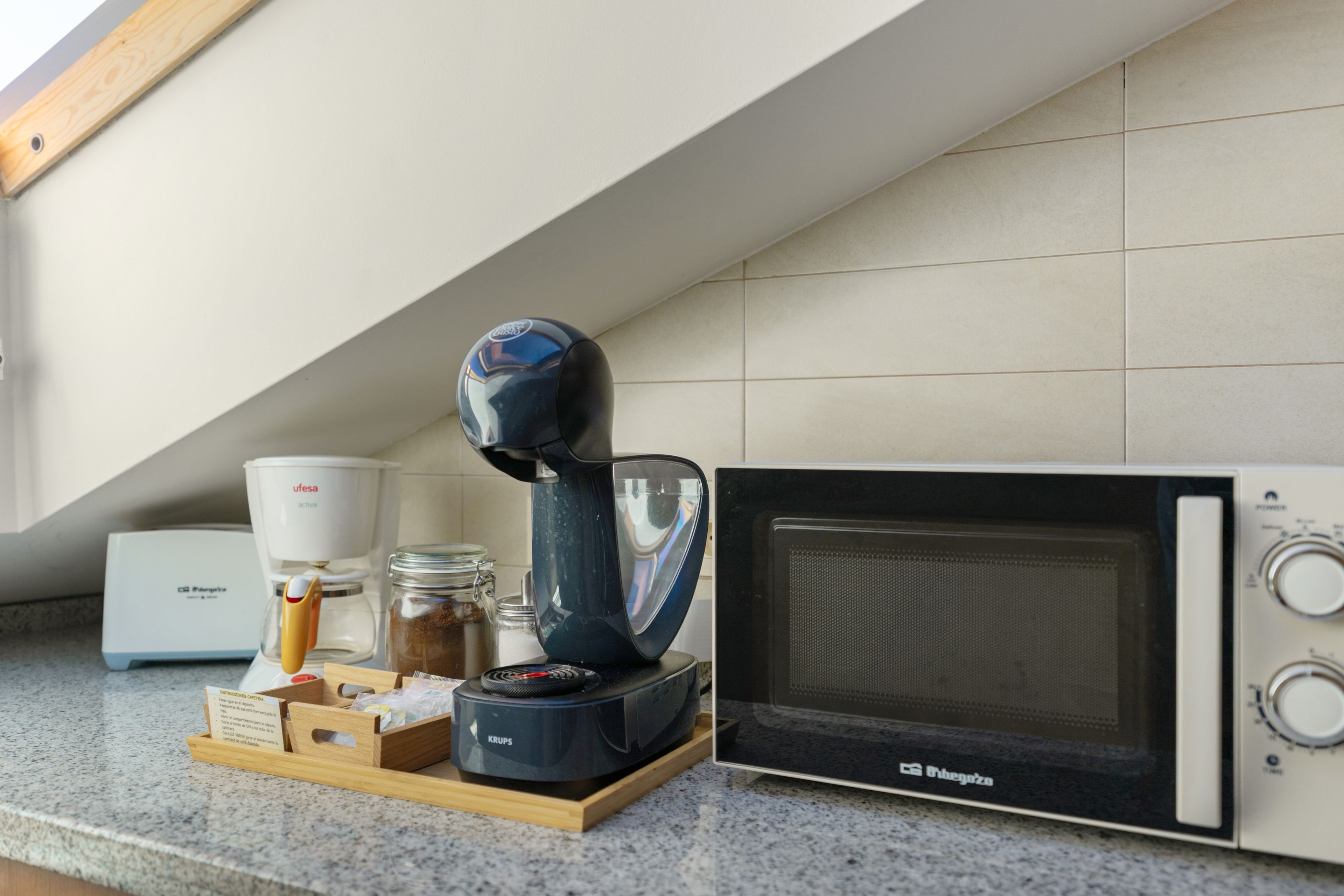Une cuisine équipée d’une machine à café, d’un four à micro-ondes, d’un moulin à café et d’un meuble pour le moulin à café.