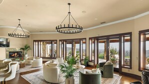 Un salon spacieux doté d’une cheminée, de grandes fenêtres et offrant une vue sur le paysage.