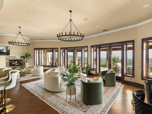 Amplia sala de estar con chimenea, ventanas grandes y vistas al paisaje.