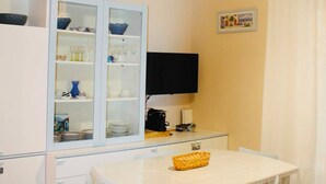 Ein Essbereich mit Tisch, Stühlen, einem Fernseher und einer Vitrine.