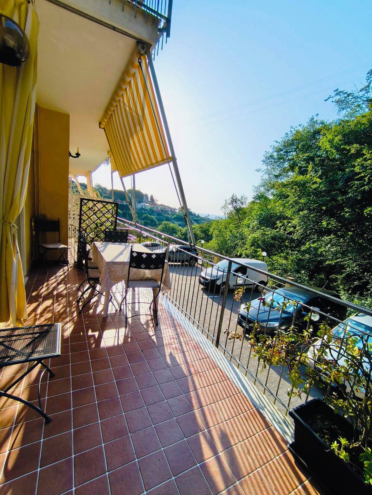 Un balcon avec un sol carrelé, une table, une chaise et une rambarde.