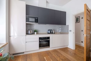 Eine moderne Küche mit weißen Schränken, einer Mikrowelle, einer Kaffeemaschine und einem Backofen.
