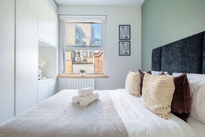 A bedroom with a large bed, a window with a view of buildings, and a headboard. - Prime Fitzrovia Location - Stylish 1BR (London)