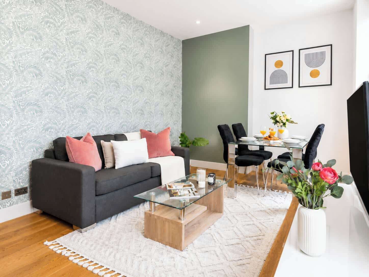 Een moderne woonkamer met een bank, salontafel, eettafel, stoelen en een televisie.