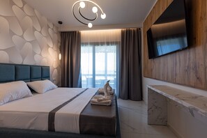 A modern hotel room with a large bed, a TV mounted on the wall, and a view of the outdoors through the window.
