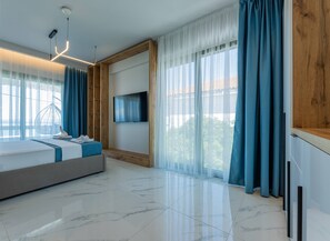A modern bedroom with a bed, a TV, and a large window with curtains.