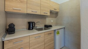 A compact kitchen with wooden cabinets, a stainless steel sink, a coffee maker, and a mini fridge.