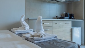 A hotel room with a bed, a small kitchenette, and a refrigerator.