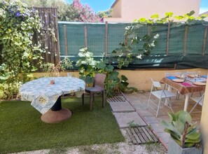 A patio area with a table and chairs, a small garden with a variety of plants, and a wooden fence. - Townhouse with a terrace (Toulon)