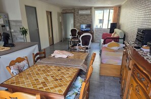 Ein kompakter Wohnbereich mit Essplatz, Fernseher, Bett und Küchenzeile.
