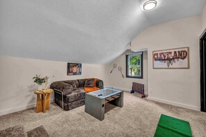 A cozy room with a sofa, a foosball table, a small side table, and a framed cityscape picture on the wall. - Near Tremont - 4BR - Sleeps 15 - Xbox (Cleveland)
