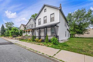 A two-story residential house with a front porch, a stone foundation, and a well-maintained lawn. - Near Tremont - 4BR - Sleeps 15 - Xbox (Cleveland)