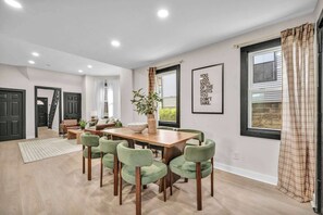 A modern dining area with a wooden table and green chairs, a potted plant, and a framed motivational quote on the wall. - Near Tremont - 4BR - Sleeps 15 - Xbox (Cleveland)