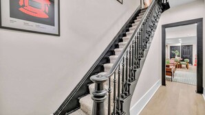 Eine Treppe mit schwarzer Brüstung und Teppichstufen, die zu einem Raum mit Essbereich führt.