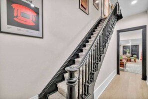 Eine Treppe mit schwarzer Brüstung und Teppichstufen, die zu einem Raum mit Essbereich führt.