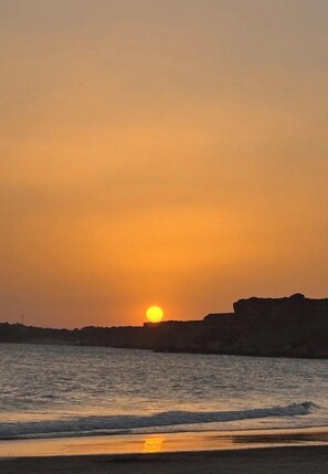 Ein Sonnenuntergang über einem Gewässer mit felsiger Küste.