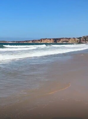 A beach with waves, a clear sky, and rocky cliffs in the background. - Townhouse in the Fuente del Sol neighborhood - Conil de la Frontera - Cádiz (Conil de la Frontera)
