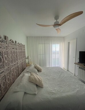 A bedroom with a bed, a ceiling fan, a TV, and a window with curtains. - Townhouse in the Fuente del Sol neighborhood - Conil de la Frontera - Cádiz (Conil de la Frontera)