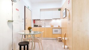 A compact living space with a kitchenette, a dining area, and a bed. - Art Home Apartments (Aveiro)