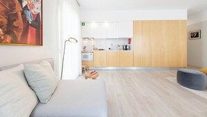 A modern living room with a sofa, a small table, and a grey ottoman. - Art Home Apartments (Aveiro)