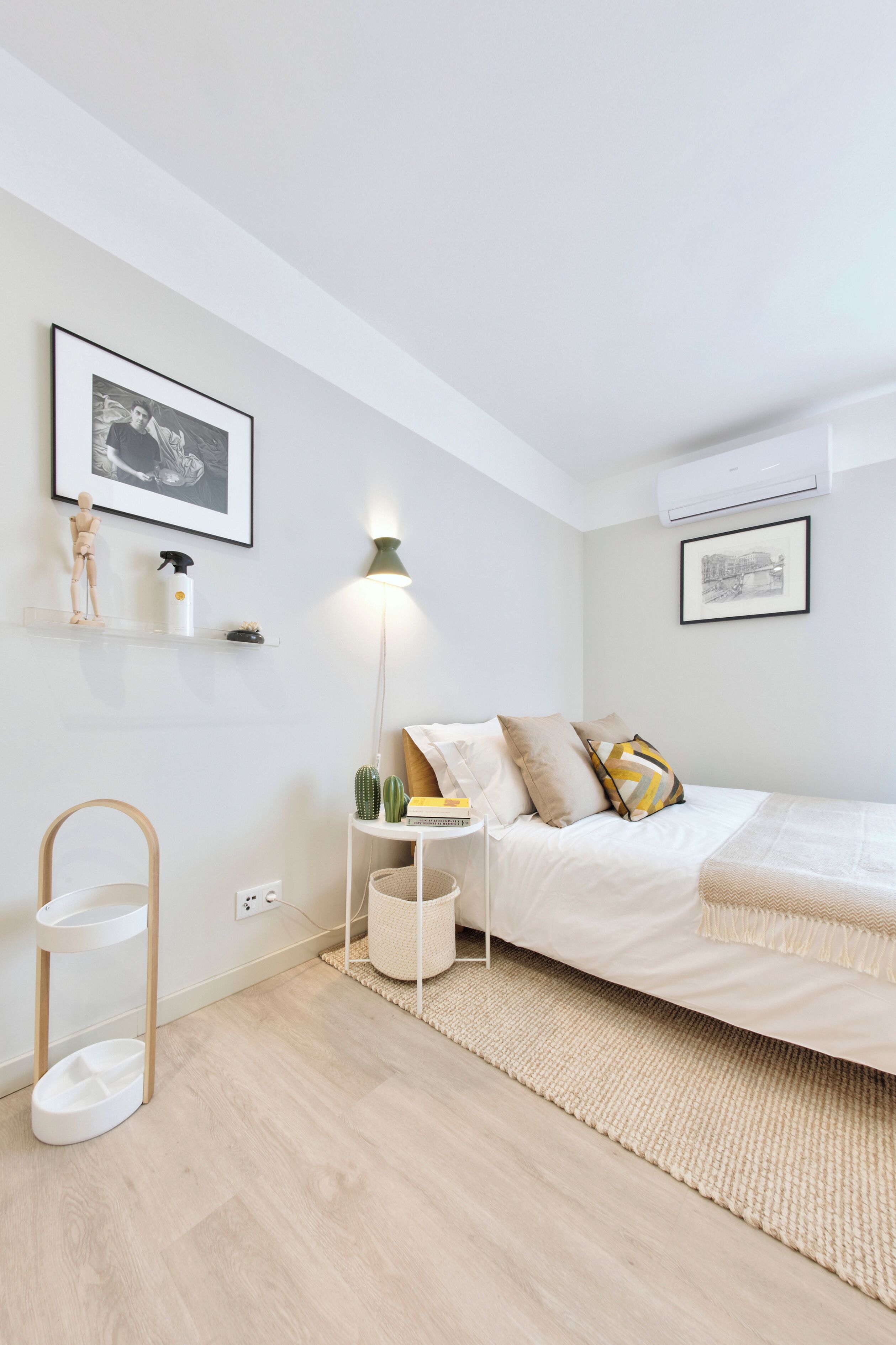 Un dormitorio minimalista con cama, mesita de noche, lámpara y estante de pared.