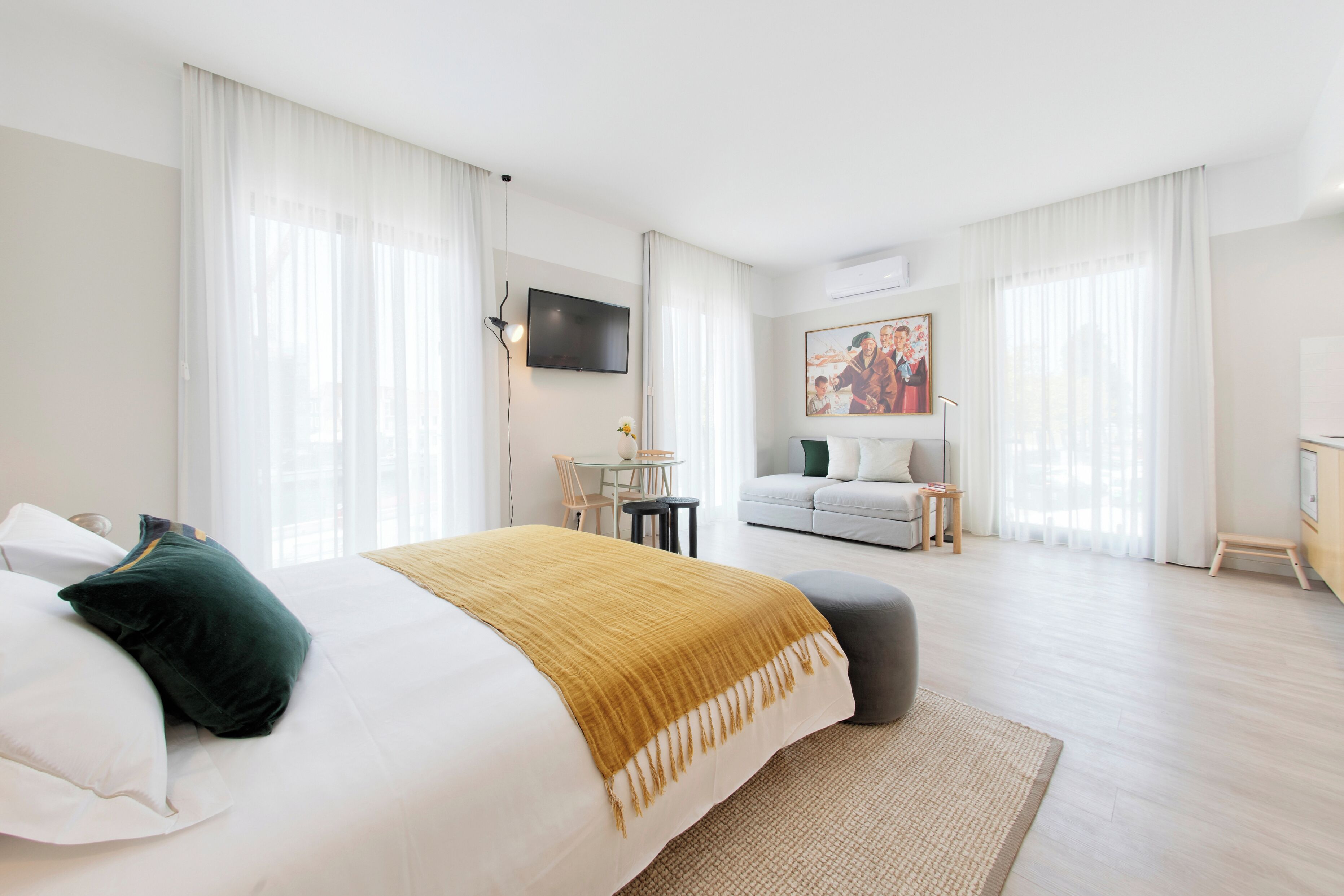 Una habitación de hotel con cama, sofá, televisión y un cuadro en la pared.