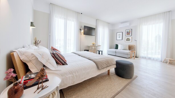 A modern bedroom with a bed, bedside table, and a TV mounted on the wall. - Art Home Apartments (Aveiro)