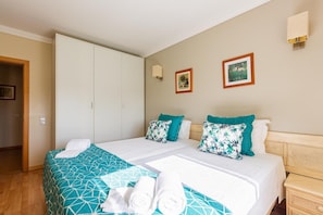 A hotel room with two beds, a wardrobe, a bedside table, and two wall-mounted lamps. - Casa Colina – Spacious Villa w/ Pool Near Beach! (Albufeira)