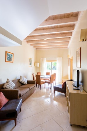 A room with a sofa, a dining table with chairs, a TV, and a desk. - Casa Colina – Spacious Villa w/ Pool Near Beach! (Albufeira)