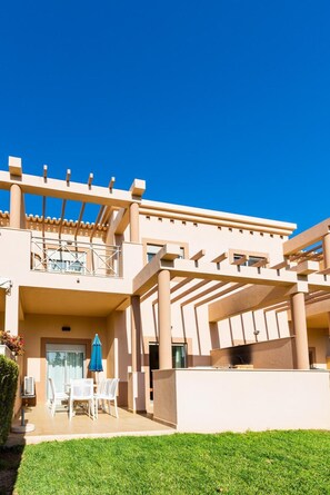A modern building with a balcony, outdoor seating, and a clear blue sky. - Casa Colina – Spacious Villa w/ Pool Near Beach! (Albufeira)