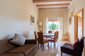 A living room with a sofa, a chair, a dining table with chairs, and a door. - Casa Colina – Spacious Villa w/ Pool Near Beach! (Albufeira)