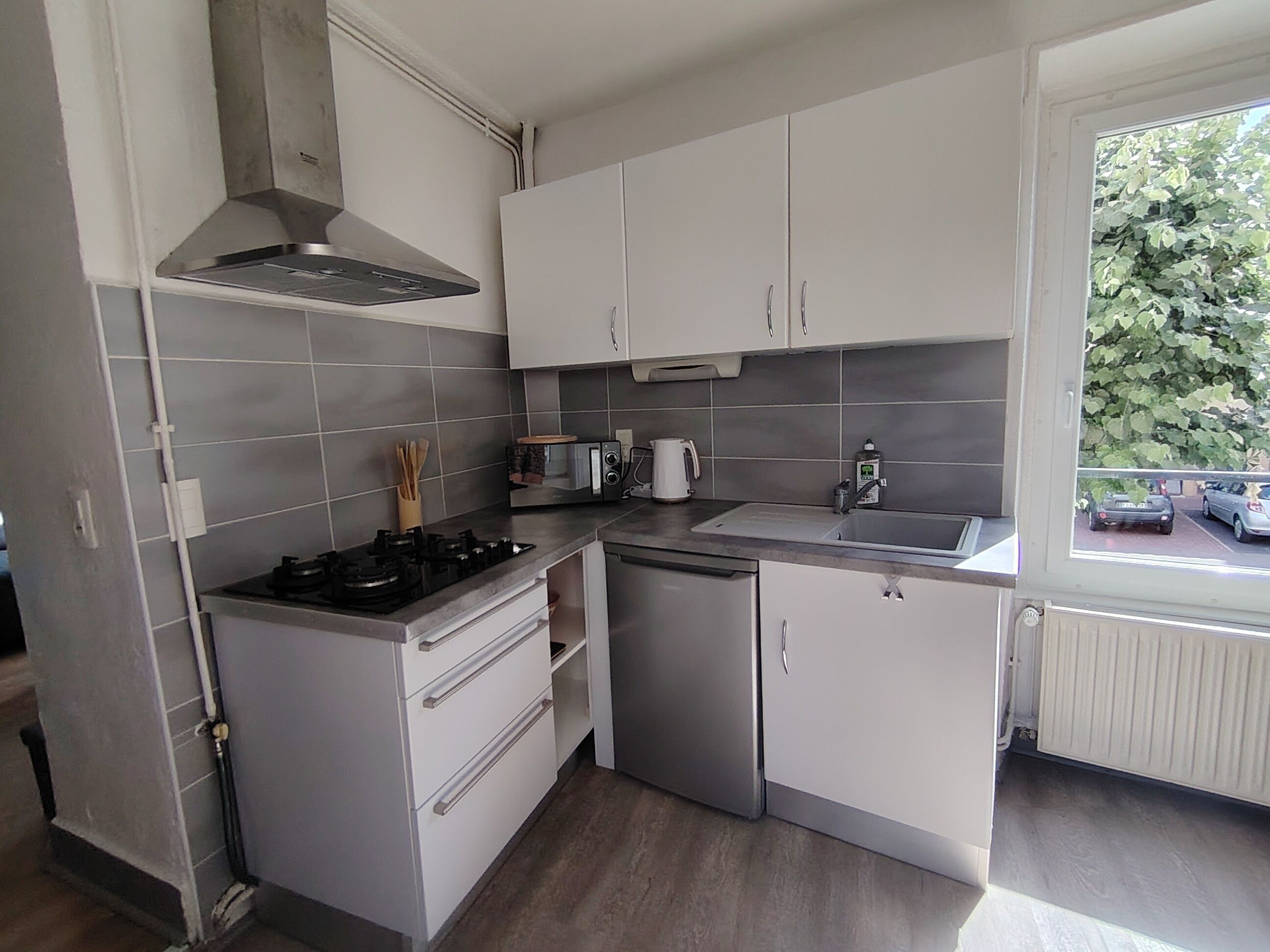 A compact kitchen with a gas stove, a sink, and white cabinets.