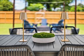 Un patio con una mesa redonda, dos lámparas y una planta verde como centro de mesa.